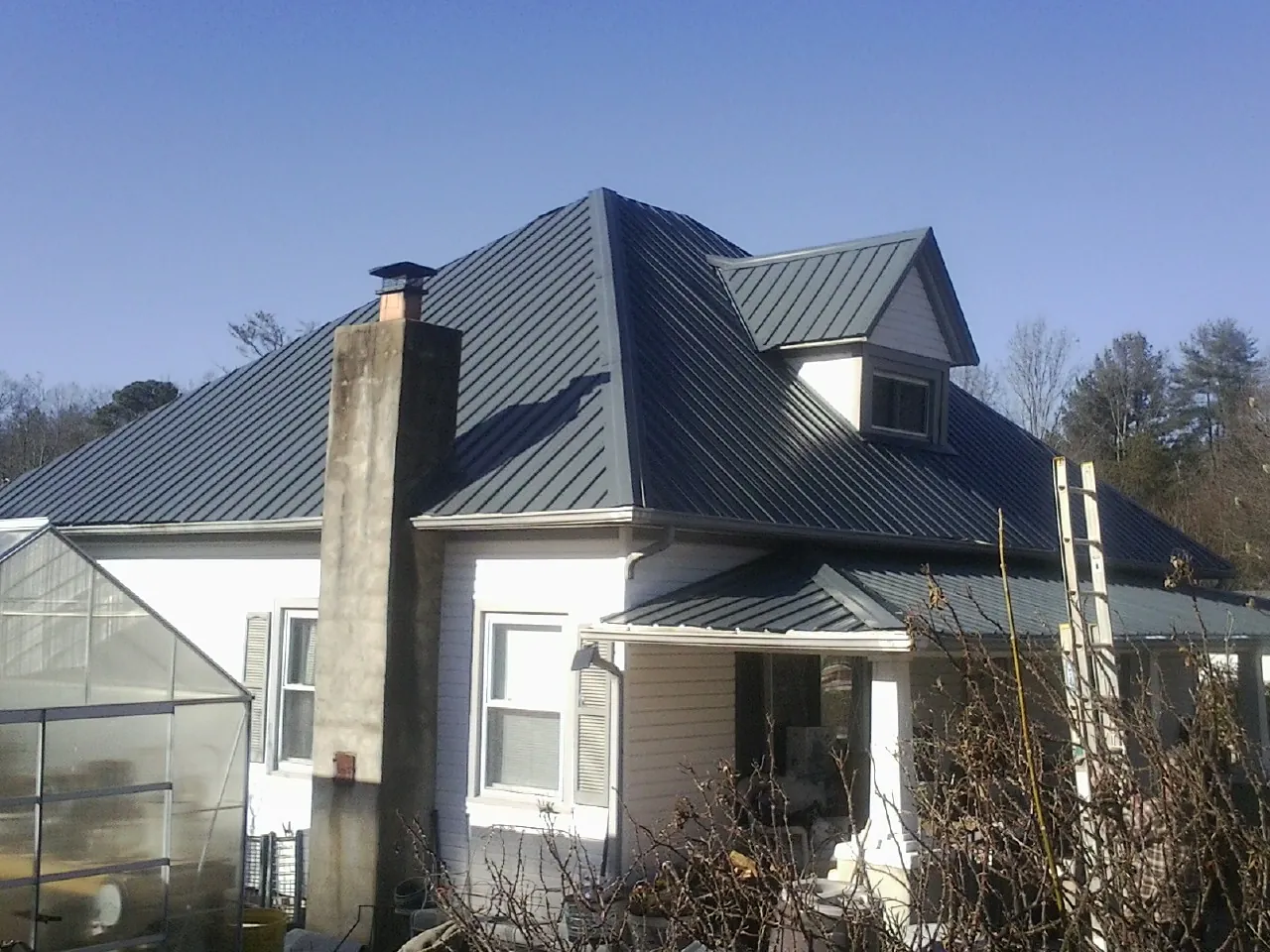 Dark blue standing seam metal roof on a white farmhouse with dormer — Slate & Tile Roof Repair by Roofing Brothers in Owings Mills