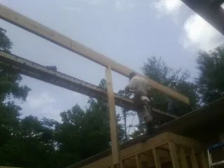 Carpenter setting a ridge beam over a new addition frame — Ice Dam Removal by Roofing Brothers in Owings Mills