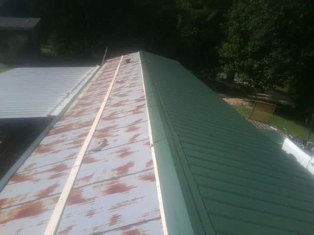 Old rusted panels beside newly installed green metal roofing — Wind Damage Roof Repair by Roofing Brothers in Owings Mills