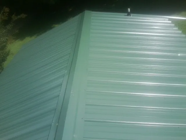 New green metal panels meeting at the ridge of a roof — Flat Roof Repair work by our crew in Owings Mills