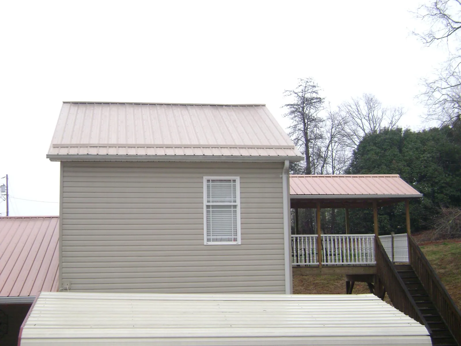 Tan metal roofs on a two story addition and attached porch, from a Roof Replacement job in Owings Mills