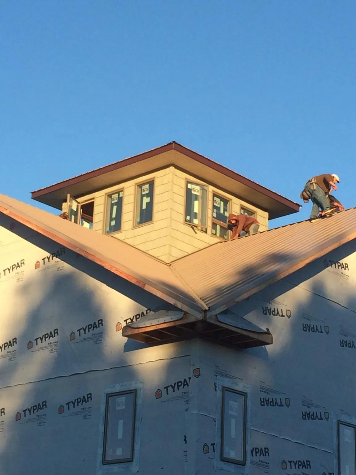 Roofers working around a rooftop cupola on a new metal roof at sunset — Roof Waterproofing in Owings Mills by Roofing Brothers